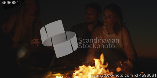 Image of Couple enjoying with friends at night on the beach