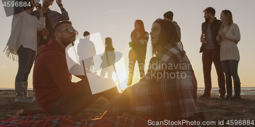 Image of Friends having fun at beach on autumn day