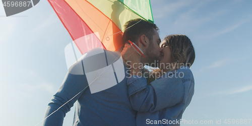 Image of Happy couple having fun with kite on beach