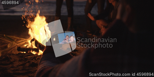 Image of Couple taking photos beside campfire on beach