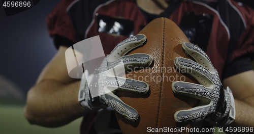 Image of American football player holding ball while running on field