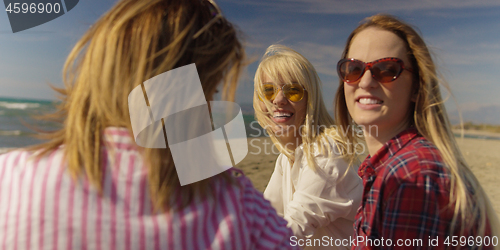 Image of Group of girlfriends having fun on beach during autumn day