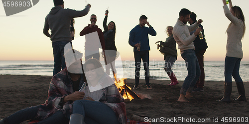 Image of Friends having fun at beach on autumn day