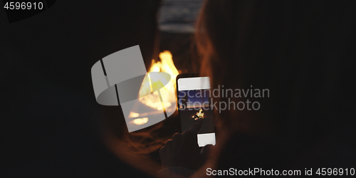 Image of Couple taking photos beside campfire on beach