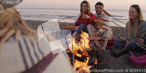 Image of Group Of Young Friends Sitting By The Fire at beach