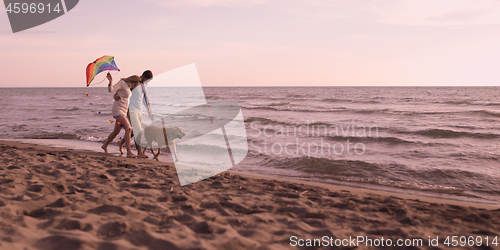 Image of couple with dog having fun on beach on autmun day