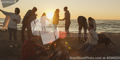 Image of Friends having fun at beach on autumn day