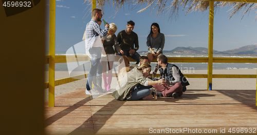 Image of Group of friends having fun on autumn day at beach