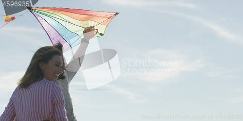 Image of Happy couple having fun with kite on beach