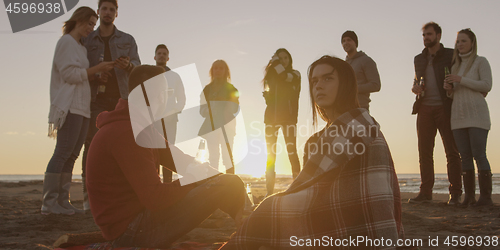 Image of Friends having fun at beach on autumn day