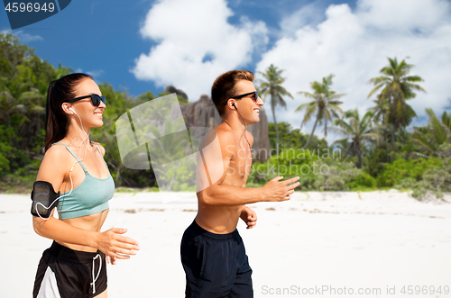 Image of couple with phones and arm bands running on beach