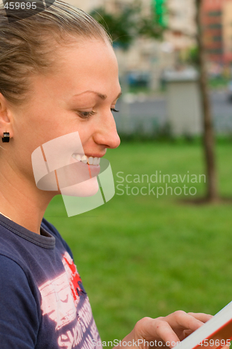 Image of attractive woman reading in the park