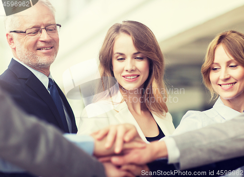 Image of business people putting hands on top in office