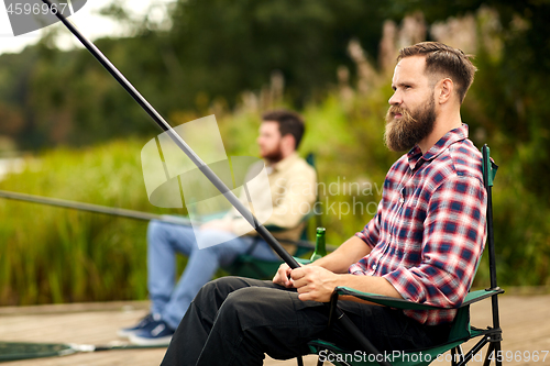 Image of bearded man with friend fishing at lake