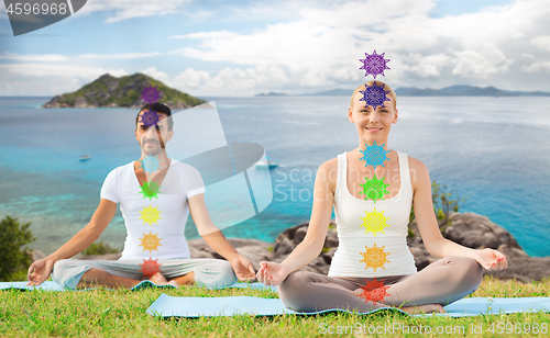 Image of couple doing yoga in lotus pose with seven chakras