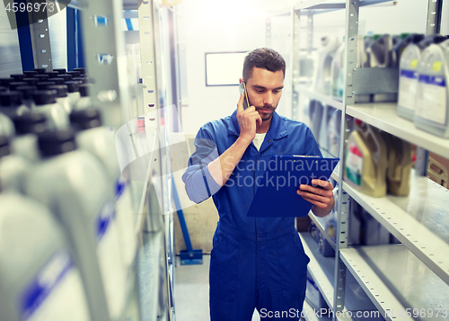 Image of auto mechanic calling on smartphone at car shop