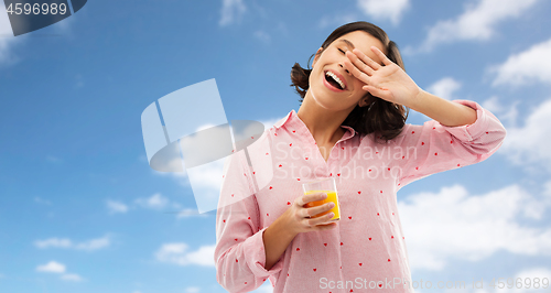 Image of happy yawning young woman in pajama with juice