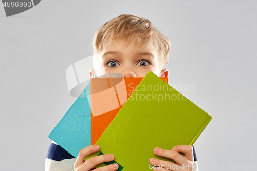 Image of shy schoolboy hiding behind books