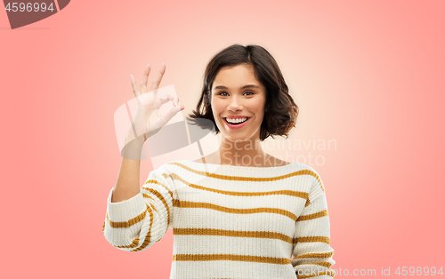 Image of happy smiling woman in striped pullover showing ok