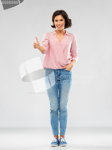 Image of young woman in shirt and jeans showing thumbs up