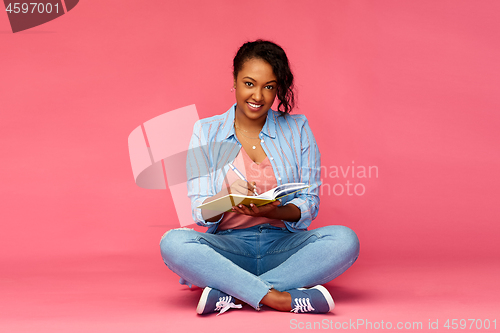 Image of african student woman writing to diary or notebook