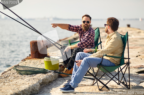 Image of happy friends with fishing rods on pier