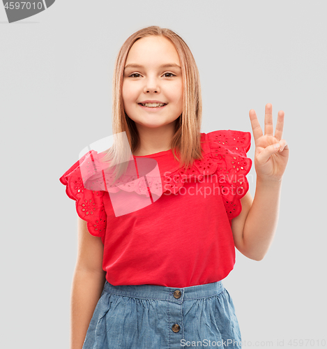 Image of smiling girl in red shirt showing three fingers