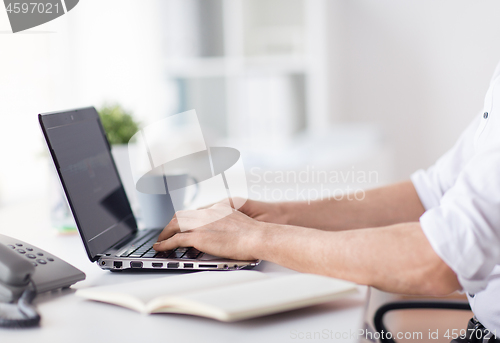 Image of close up of businessman typing on laptop at office