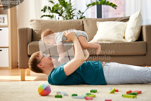 Image of happy father with little baby son playing at home