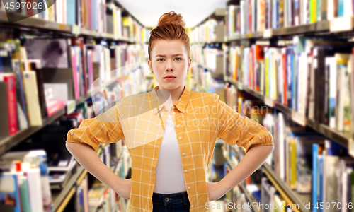 Image of displeased red haired student girl at library