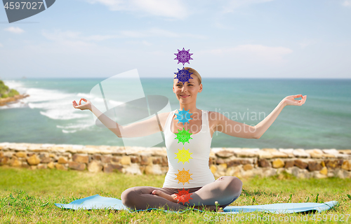 Image of woman doing yoga in lotus pose with seven chakras