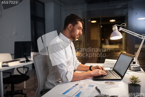 Image of businessman with laptop working at night office