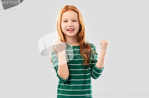 Image of smiling red haired girl celebrating success