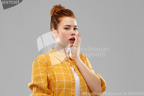 Image of red haired teenage girl covering mouth by hands