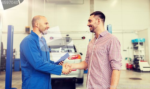 Image of auto mechanic and man shaking hands at car shop