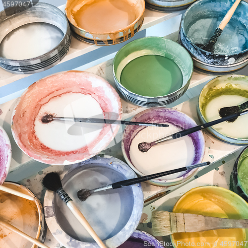 Image of Paint brushes in colorful ceramic plates