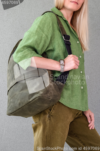 Image of Woman in green clothes holding backpack