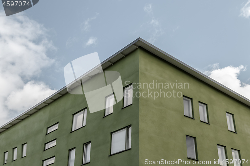 Image of Corner of green building against blue sky