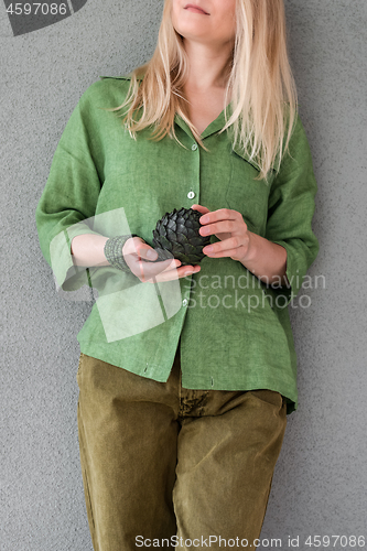 Image of Woman in green clothes holding artichoke