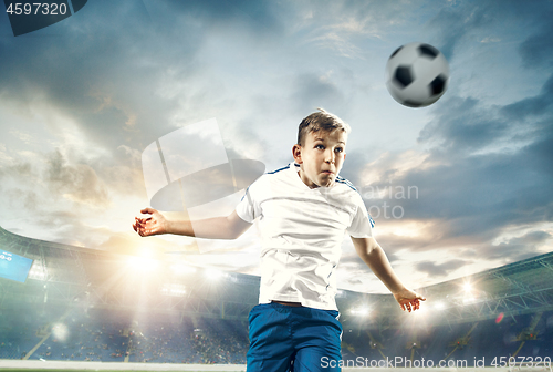 Image of Young boy with soccer ball doing flying kick at stadium