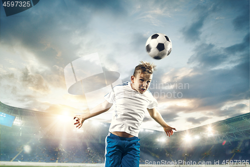 Image of Young boy with soccer ball doing flying kick at stadium