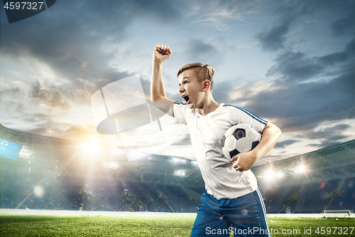 Image of Young boy with soccer ball doing flying kick at stadium