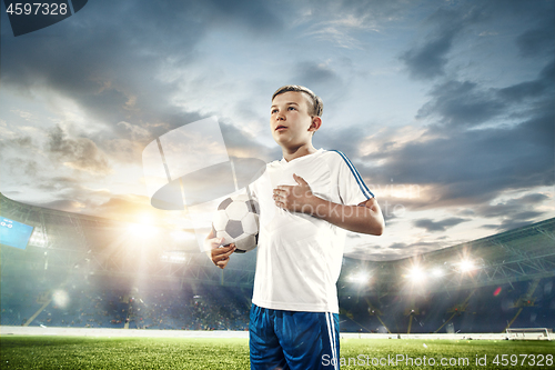 Image of Young boy with soccer ball doing flying kick at stadium