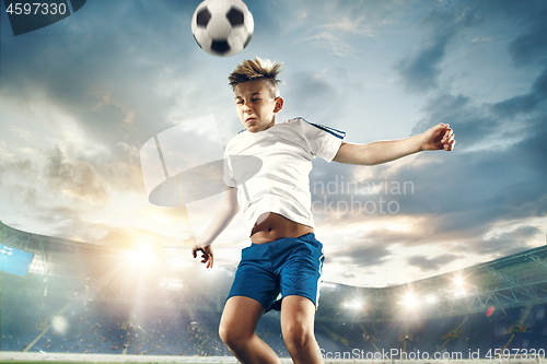 Image of Young boy with soccer ball doing flying kick at stadium