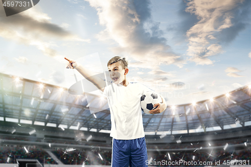 Image of Young boy with soccer ball doing flying kick at stadium