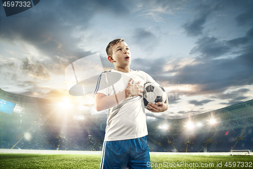 Image of Young boy with soccer ball doing flying kick at stadium