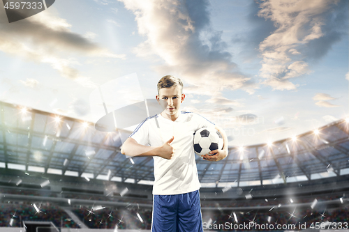 Image of Young boy with soccer ball doing flying kick at stadium