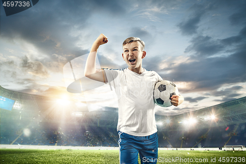 Image of Young boy with soccer ball doing flying kick at stadium