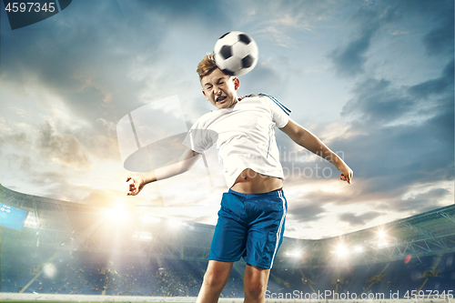 Image of Young boy with soccer ball doing flying kick at stadium