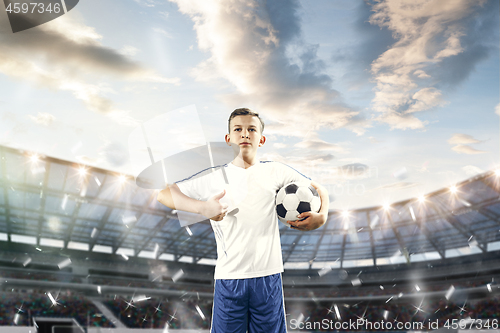 Image of Young boy with soccer ball doing flying kick at stadium